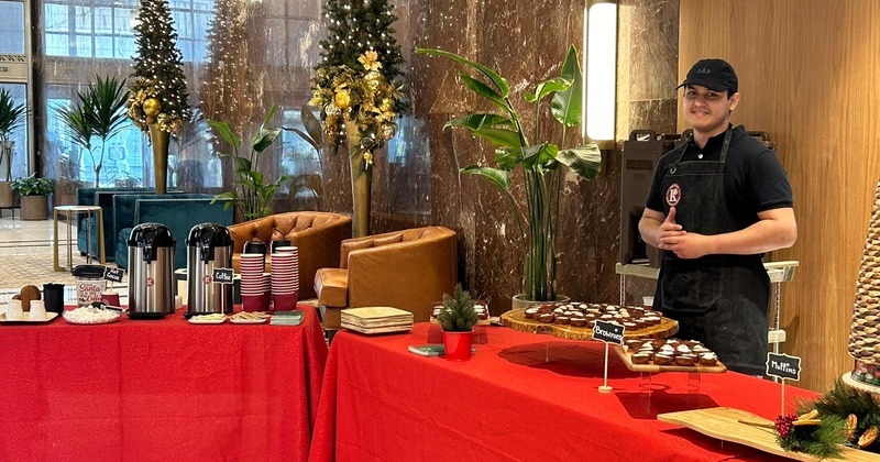 A server standing behind a table with food and drinks at an event