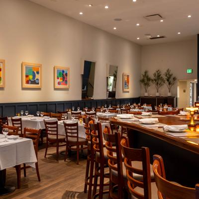 Dinig area with elegant bar seating, set tables, and colorful wall art.