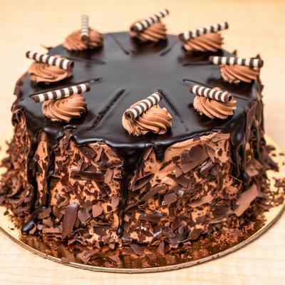 Chocolate cake decorated with chocolate shavings, whipped cream, and chocolate drizzle.
