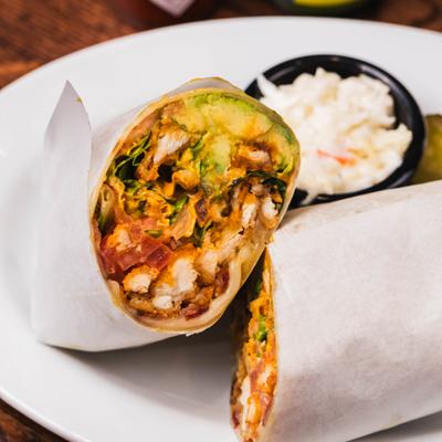 Chicken wrap, sliced in half and served with coleslaw.