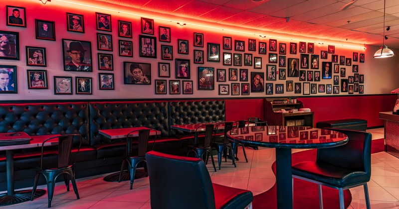 Interior of a casual pizza restaurant, seating area, framed photographs of celebrities on the wall
