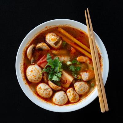 Tom yum soup with mushrooms and herbs in bowl.