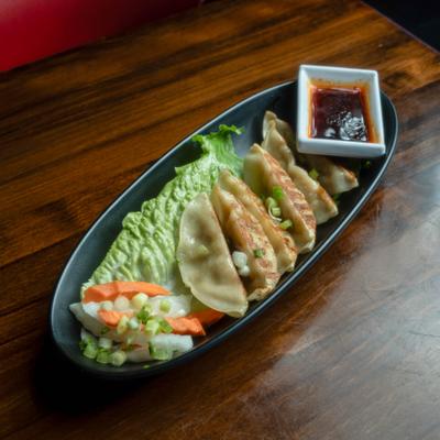 Pan-fried dumplings served with dipping sauce.