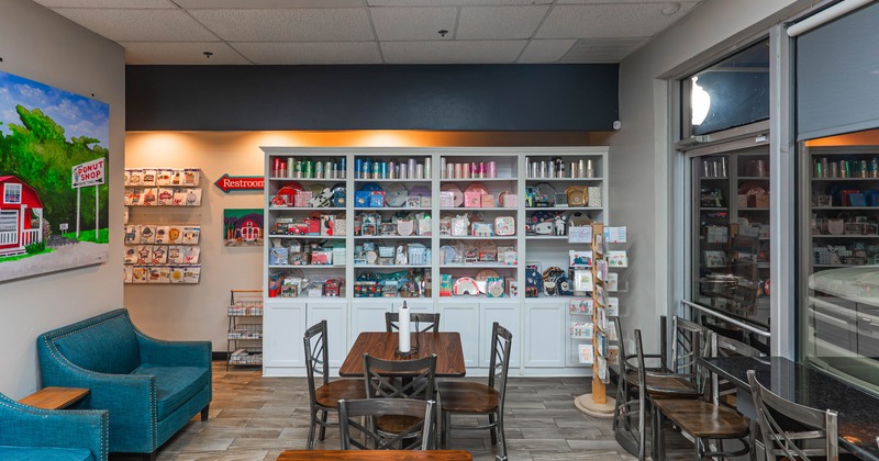 Interior of a small shop with seating, a white shelving unit filled with gifts