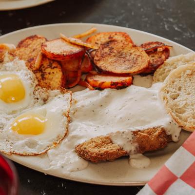 Country fried steak and gravy, with sunny side up eggs, English muffin, and potatoes.