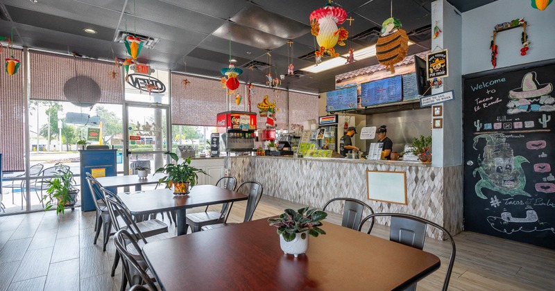 Interior - tables, potted plants, a service counter, menu boards, hanging decorations.