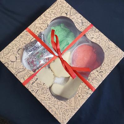 A beige box with a red ribbon contains colorful cookies.