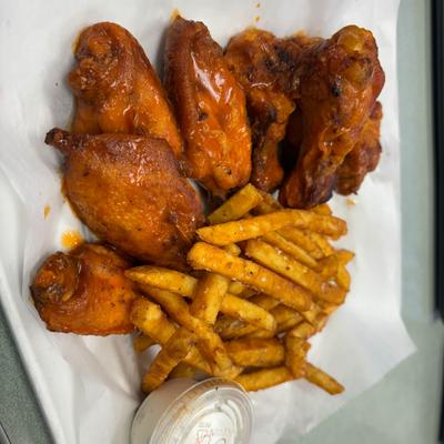 Fried chicken wings with fries and a side of dipping sauce.
