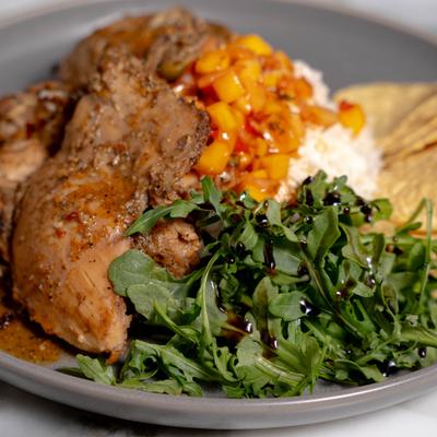 Jamaican Jerk Chicken with mango salsa served with rice and arugula.