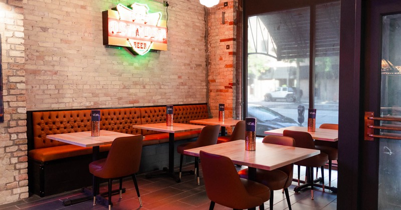Interior, button tufted banquette seating with three tables and chairs, lined up tables for two