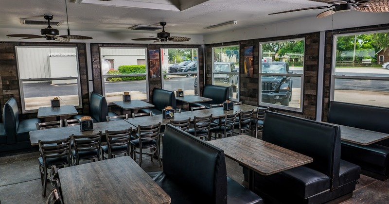 Interior of spacious and cozy dining area with tables, chairs and upholstered booths