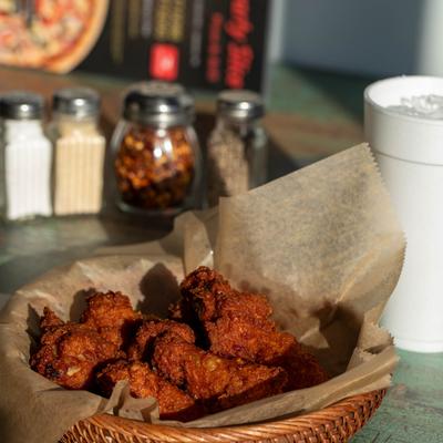 A basket of fried chicken with condiments and a soda on the table.