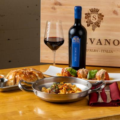 Assorted Italian dishes and red wine on a wooden table.