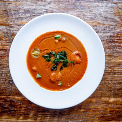 A bowl of veggie gazpacho soup on a rustic wooden table.
