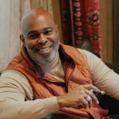 A person in an orange vest holding a cigar.