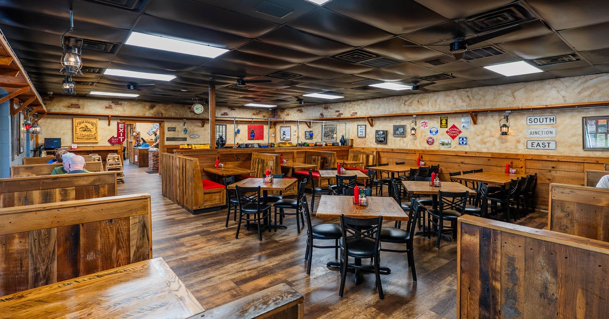Interior of a rustic restaurant, wooden tables and booths, red cushions, vintage decorations