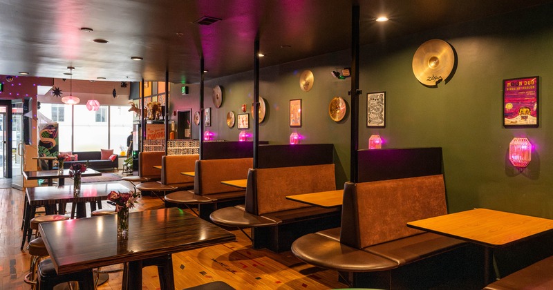 Interior seating area with wooden tables, booths and decorative cymbals on the wall