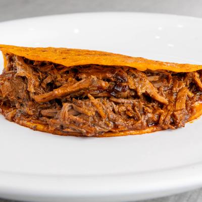 A cheesy birria taco on a white plate.