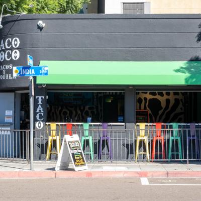 Taco Loco restaurant exterior with colorful bar stools and green awning.