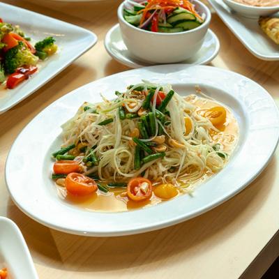 Papaya salad plate with assorted dishes around it.
