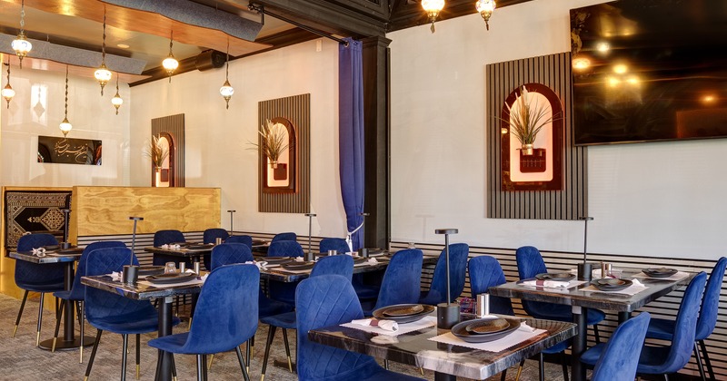 Modern and stylish restaurant interior dining area with elegant blue velvet chairs and set tables