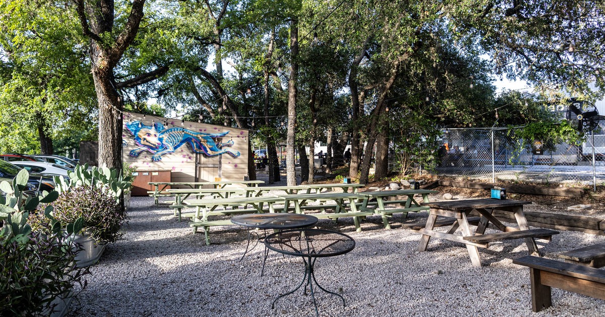 Beer garden with string lights and picnic tables under the green trees