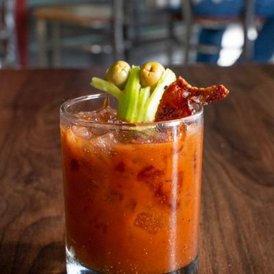 Bloody Mary cocktail garnished with bacon, celery, and olives