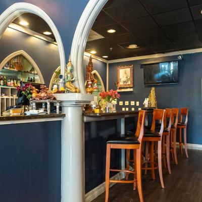 Bar area with arched architectural details, a counter and wooden bar stools.