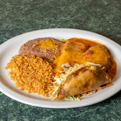 Mexican combo plate featuring a crispy taco, chile relleno, seasoned rice, and refried beans.