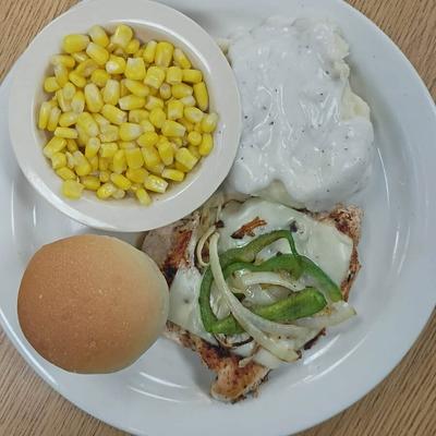 A served steak with mashed potatoes, corn, and a bun.