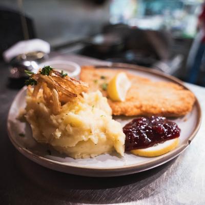 Wiener Schnitzel served with mashed potatoes topped with fried onions and lingonberry sauce.