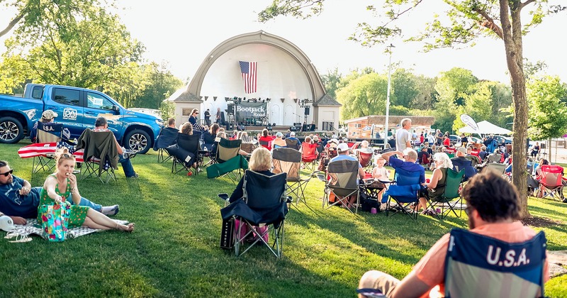 Exterior, people sitting in lawn chairs at concert