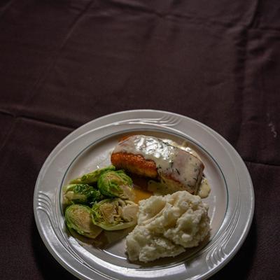 Salmon topped with a creamy sauce, served with mashed potatoes and Brussels sprouts.