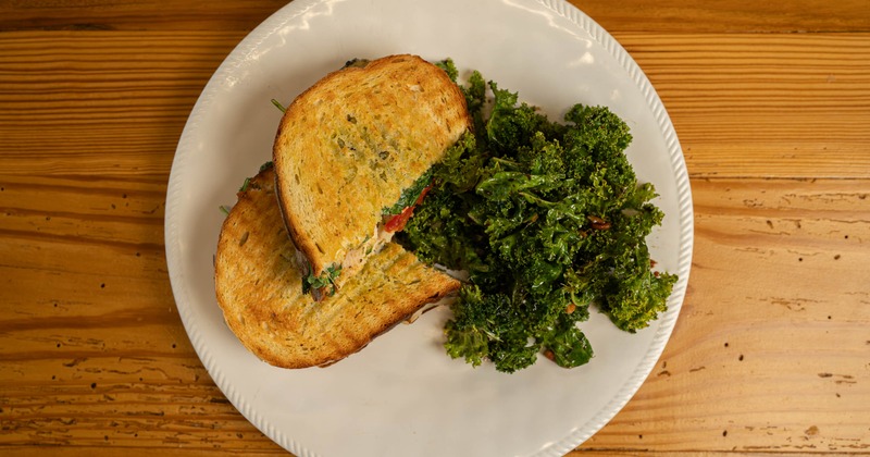 Seasoned chicken sandwich served with kale salad