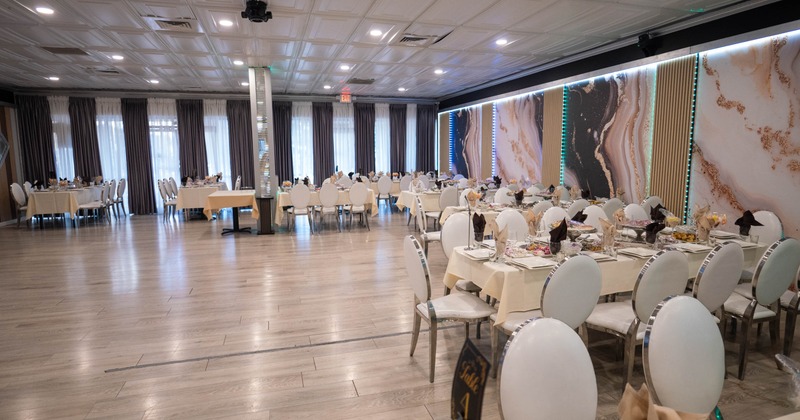 Spacious banquet hall with elegantly set tables and decorative walls.