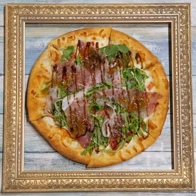 Gourmet pizza presented in a decorative gold frame.