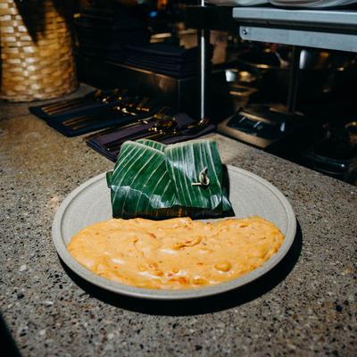 A creamy yellow dish served with a banana leaf wrap.