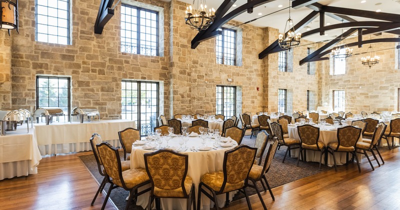 Interior, event area, stone walls, round white cloth tables for ten, catering containers