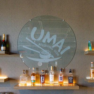 Circular mirrored sign with stylized chopsticks and a bowl alongside bottles of spirits.