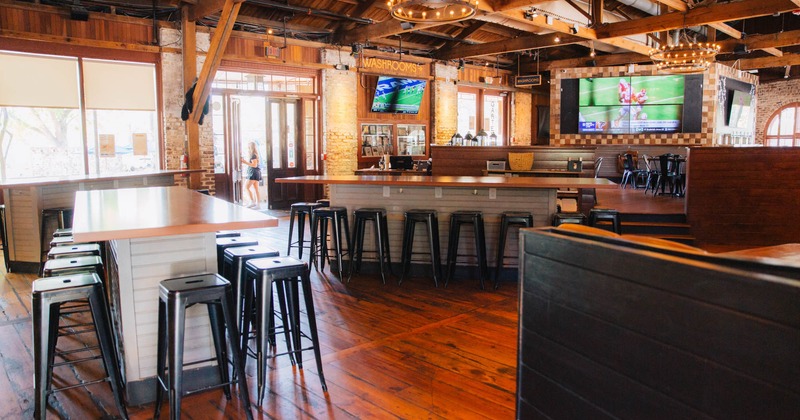 Interior, bar stools and tables, large TV, wooden flooring, large windows, restaurant entrance