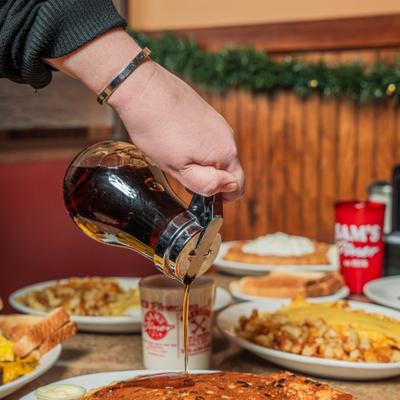 Syrup being poured over pancakes.
