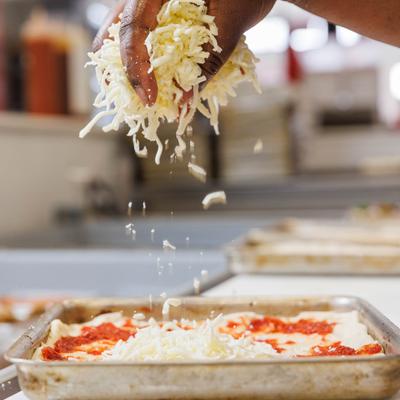 Adding cheese over pizza dough.