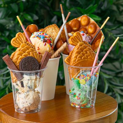 Assorted dessert cups filled with ice cream, candies, and Japanese fish-shaped pastries.