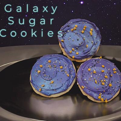 Three galaxy-themed sugar cookies with blue icing and star decorations.