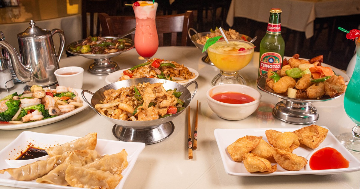 A table filled with diverse Chinese dishes, accompanied with colorful drinks