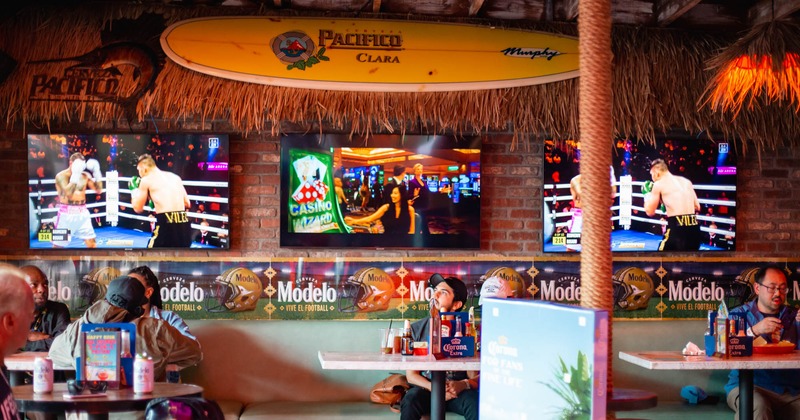 Guests in dining area, large TVs on a wall