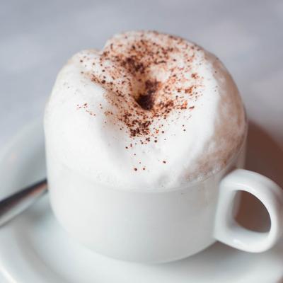 A close-up of a frothy cappuccino topped with cocoa powder.