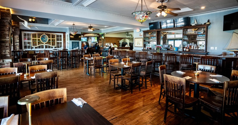 Interior view of a restaurant with wooden floors and furniture, featuring pendant lights