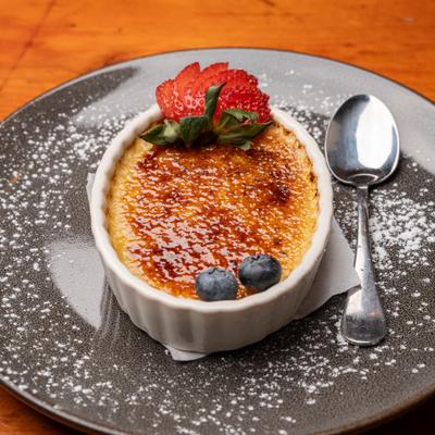 Creme brulee topped with berries and powdered sugar.