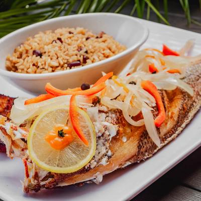 Pan fried red snapper, with onions, tomatoes, herbs, plantains, and rice and beans.